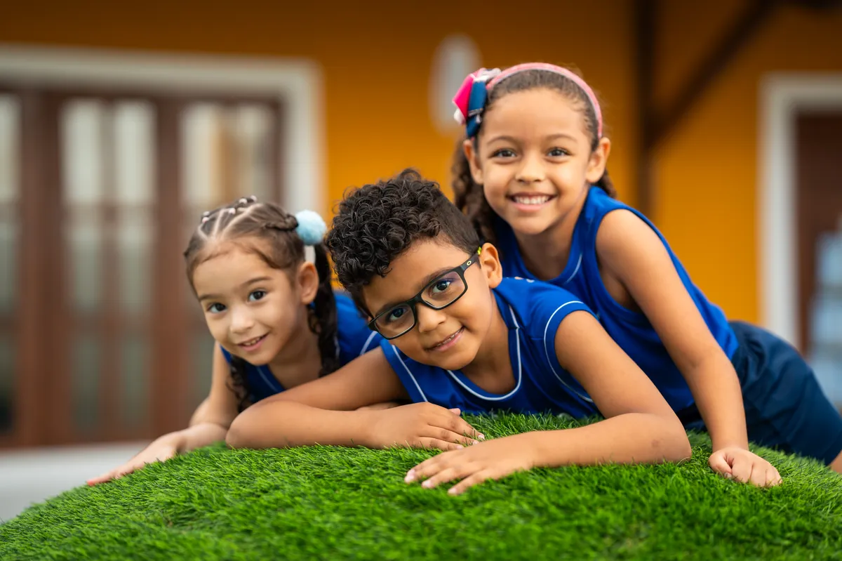 Crianças da Educação Infantil sorrindo no gramado do Darwin